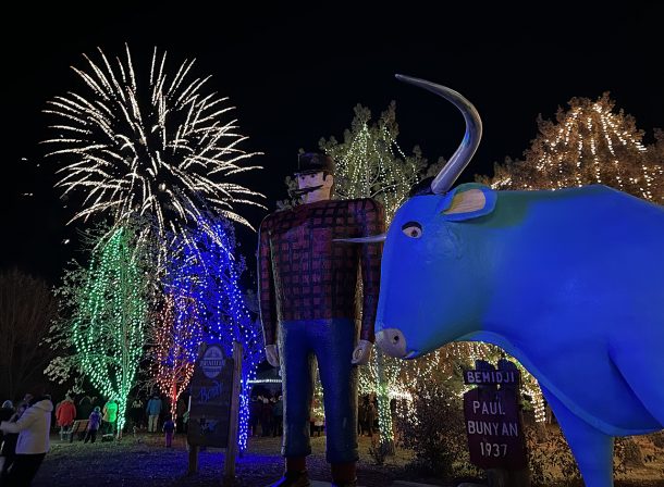 Paul Bunyan & Babe The Blue Ox with Christmas lights and fireworks in the background.